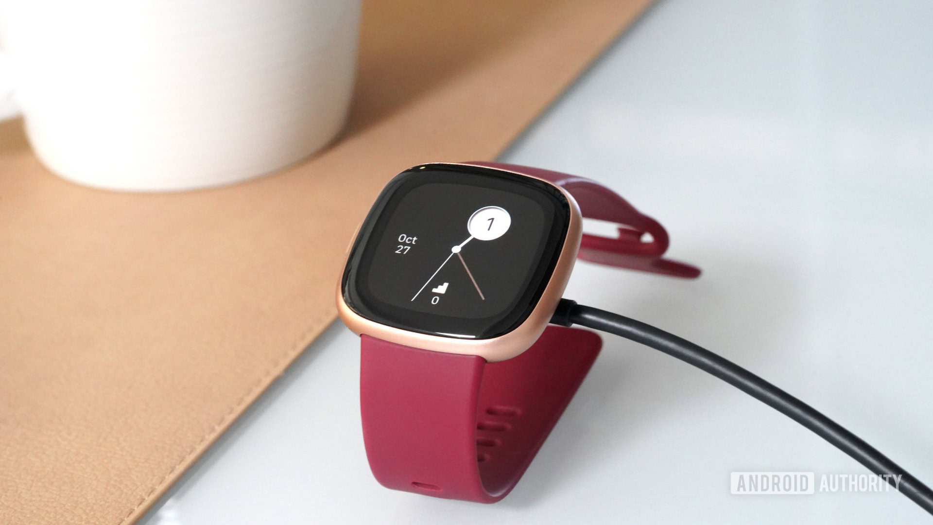 Fitbit Versa 4 Charging A Fitbit Versa 4 charges on a user's desk.