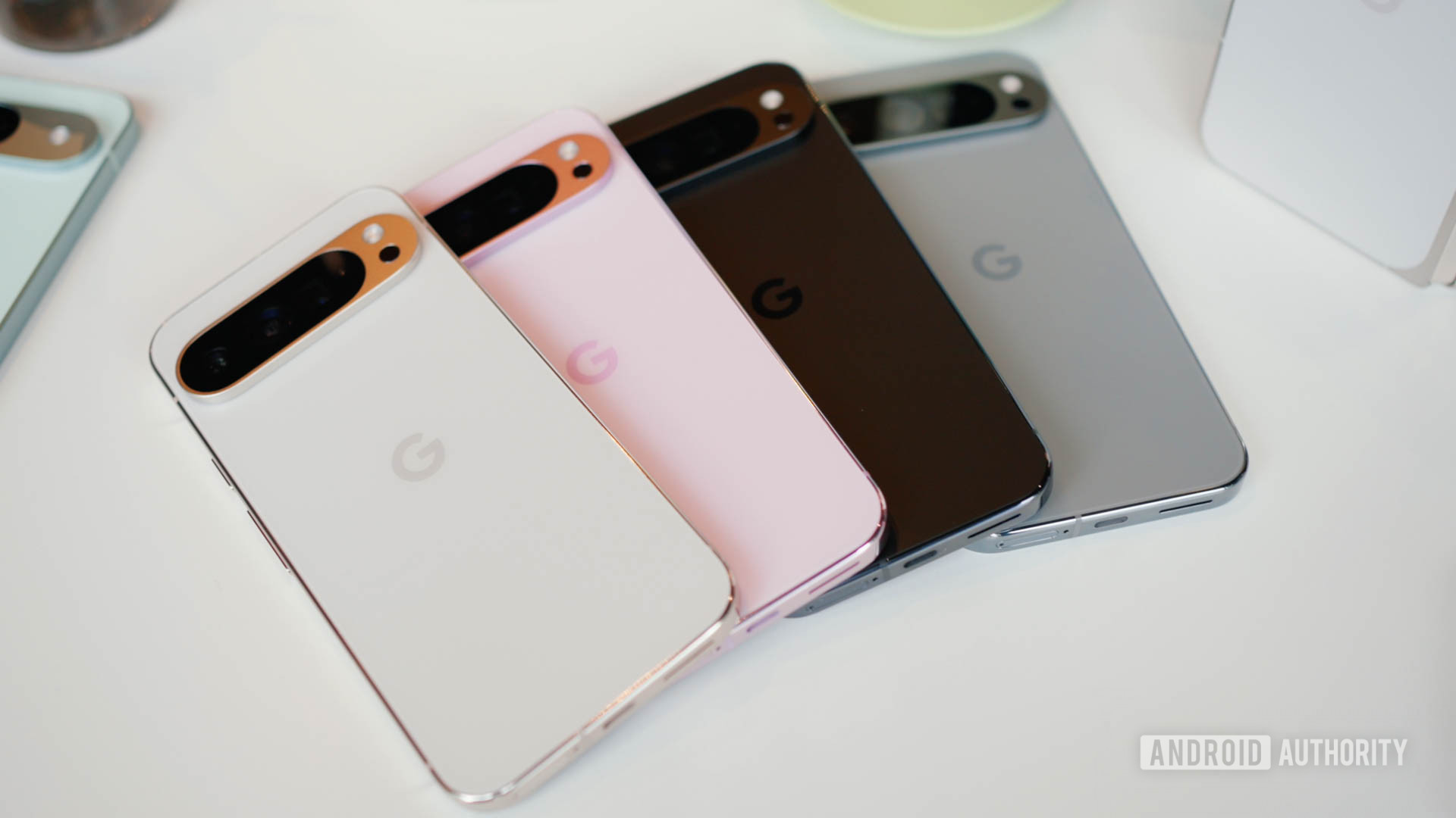 Four Pixel 9 Pro XL phones, all in different colors, laying on top of each other.