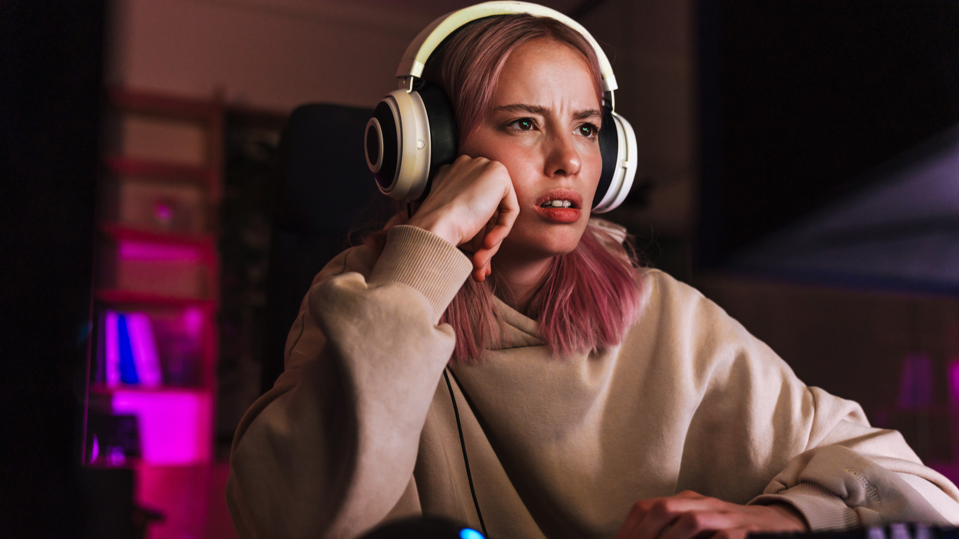 A frustrated looking girl sat at a gaming PC