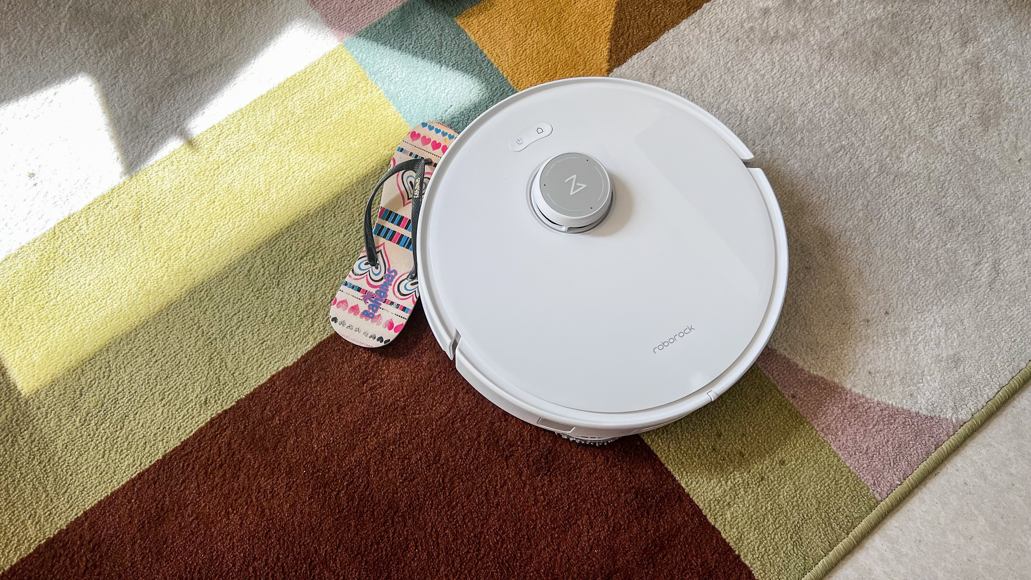 Roborock Qrevo Edge pushing a flip-flop on a carpet