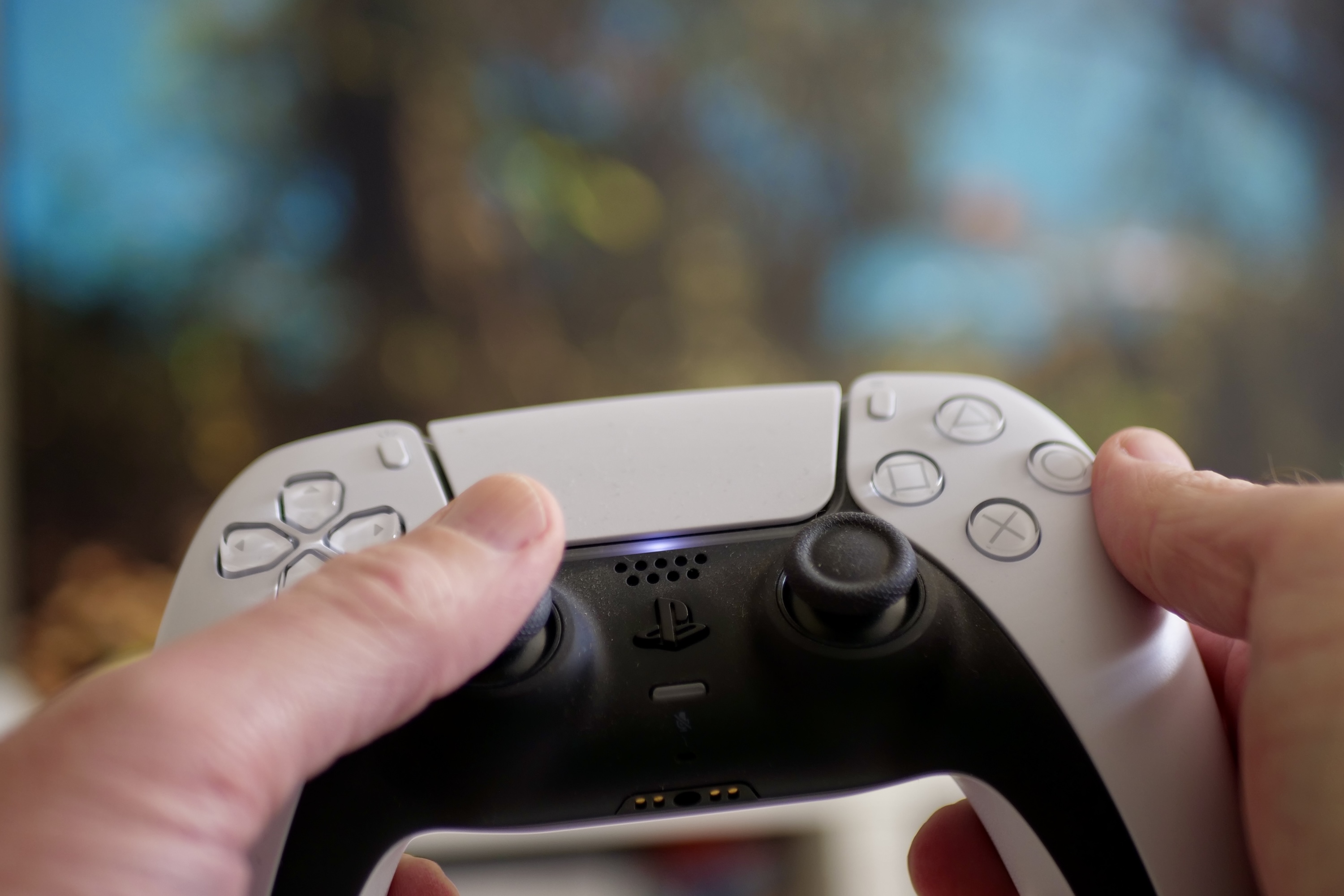 A person holding a PlayStation 5 controller.