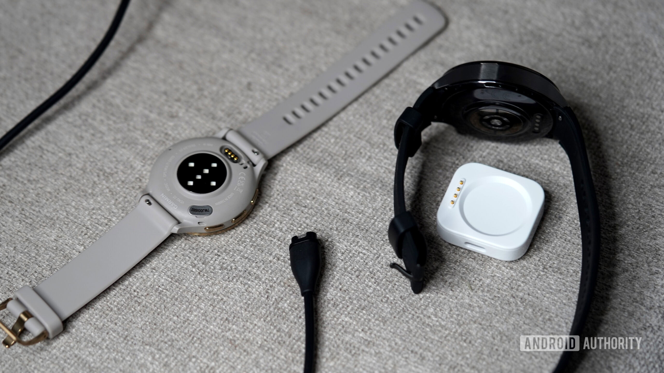 A OnePlus Watch 3 and Garmin Venu 3 rest alongside their chargers.