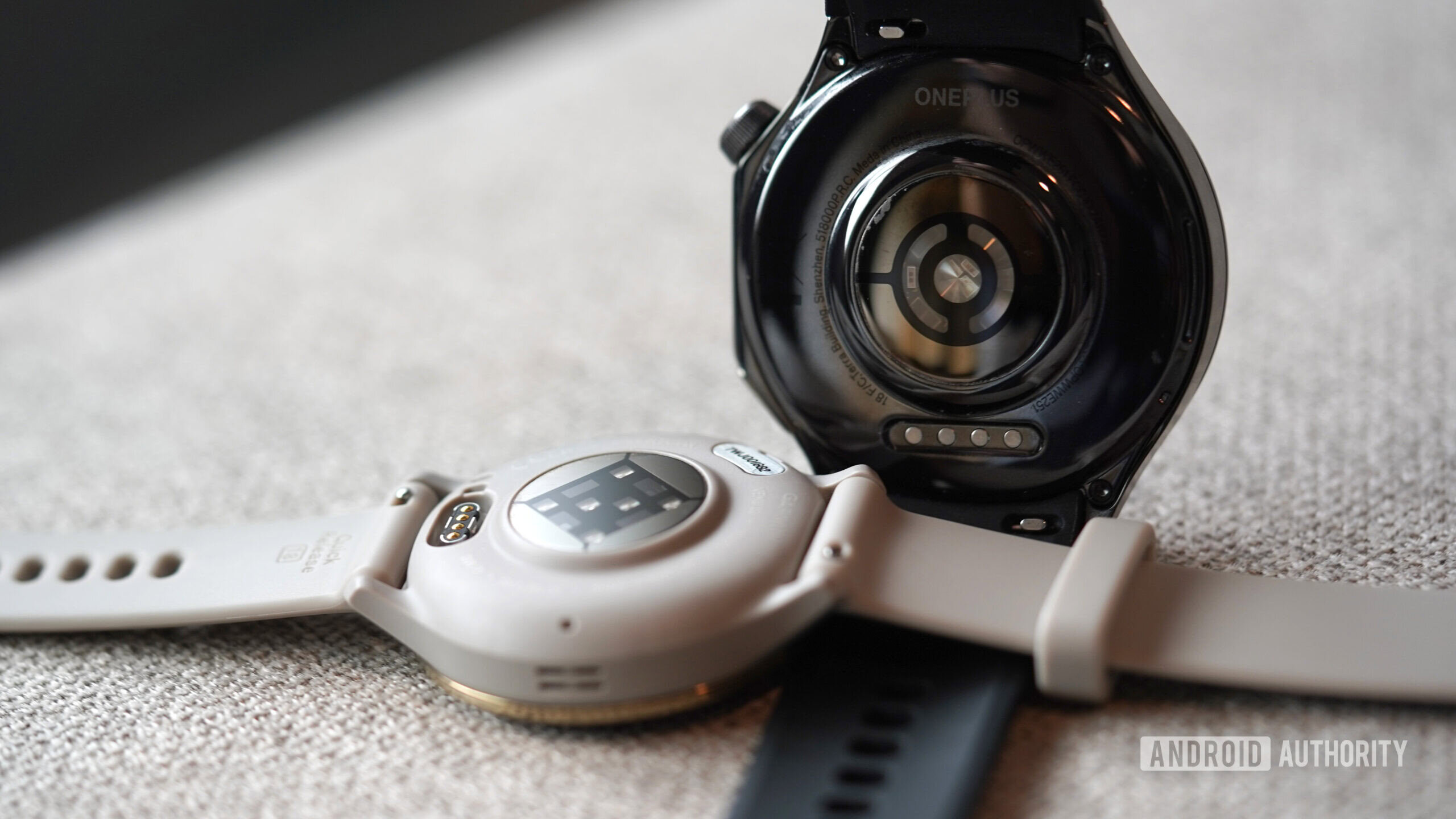 A Garmin Venu 3 and OnePlus Watch 3 rest face down displaying their sensor packages.