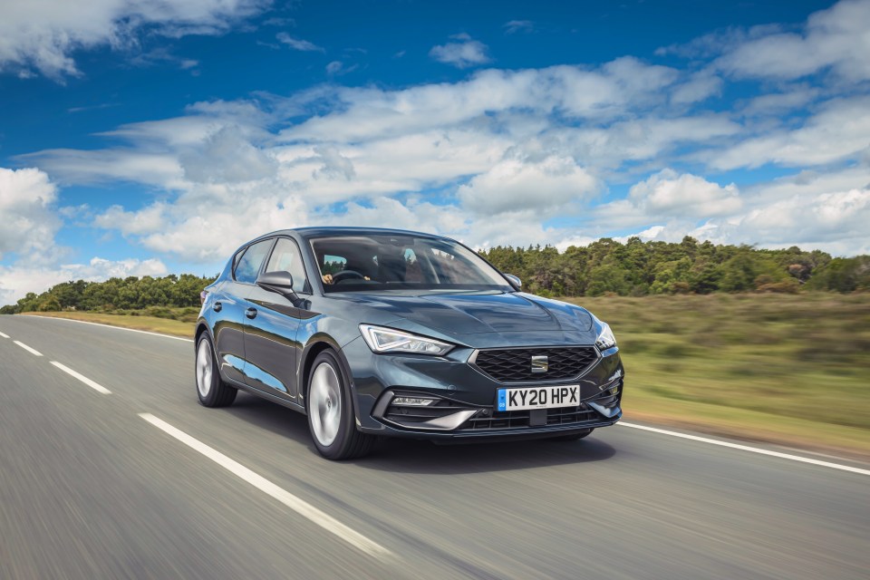 Dark-colored Seat Leon driving on a road.
