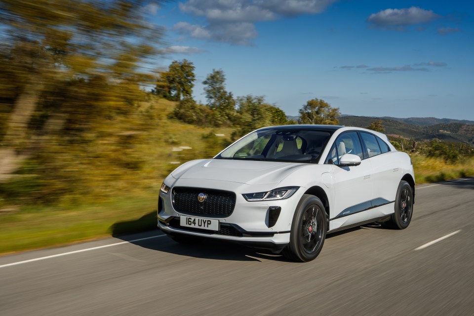 White Jaguar I-Pace driving on a road.