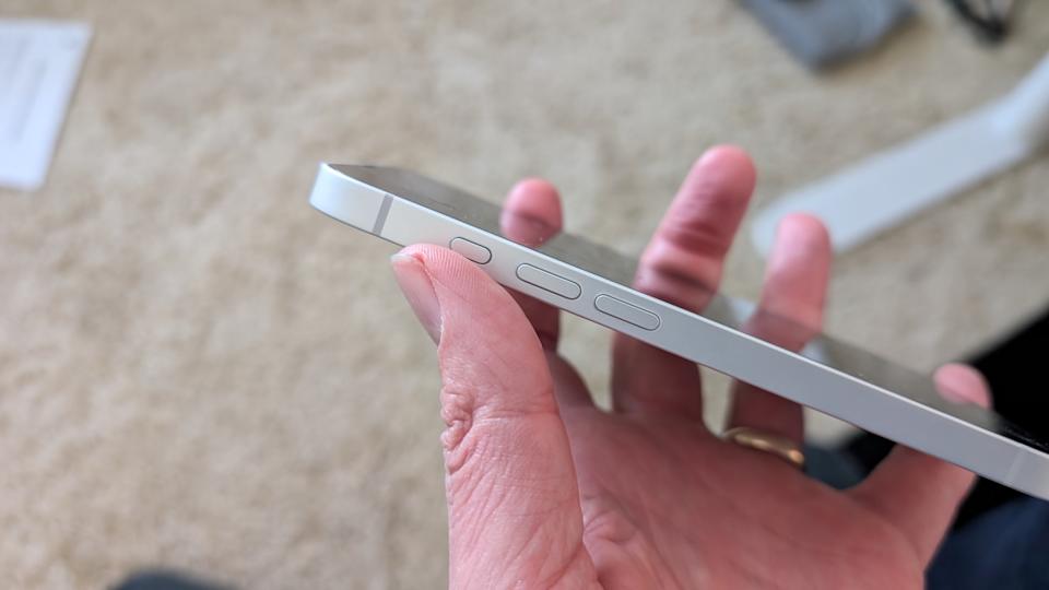 A side photo of the iPhone 16e, with the thumb resting by the Action Button that replaces the mute switch.