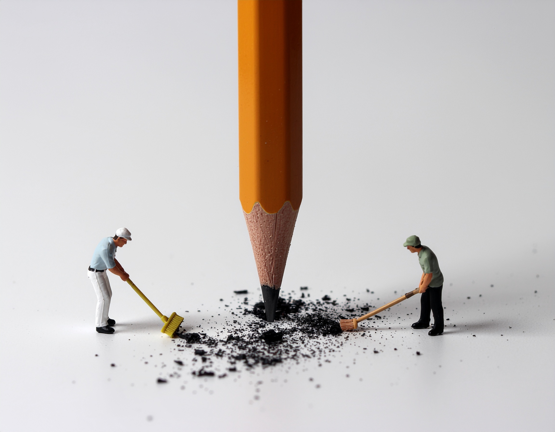 Small sweeper men, cleaning up pencil shavings from a huge pencil pointing downwards vertically, created using Adobe Firefly Image Model 4