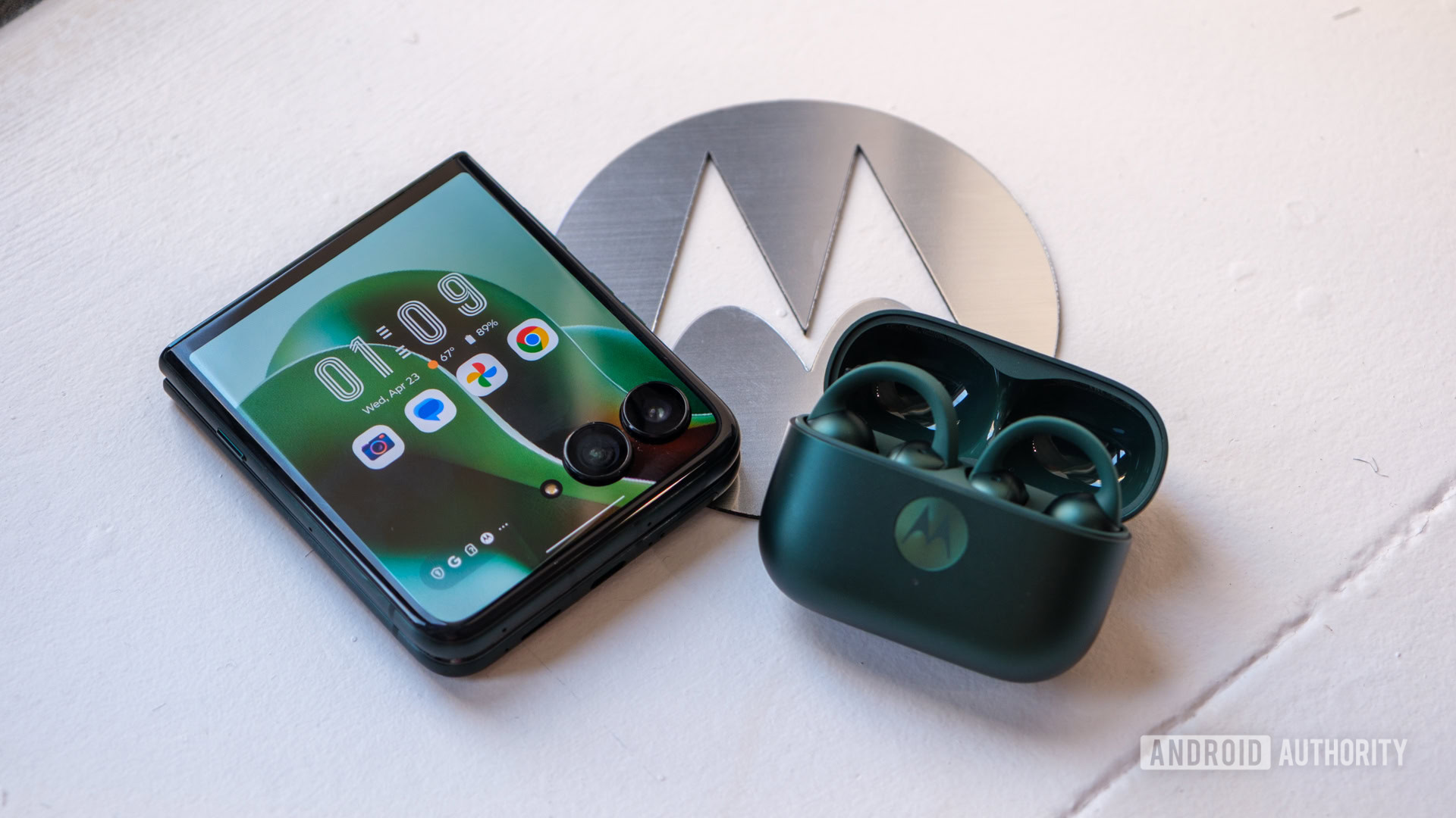 Motorola Razr Ultra with earbuds on top of logo Motorola Razr Ultra with earbuds on top of logo