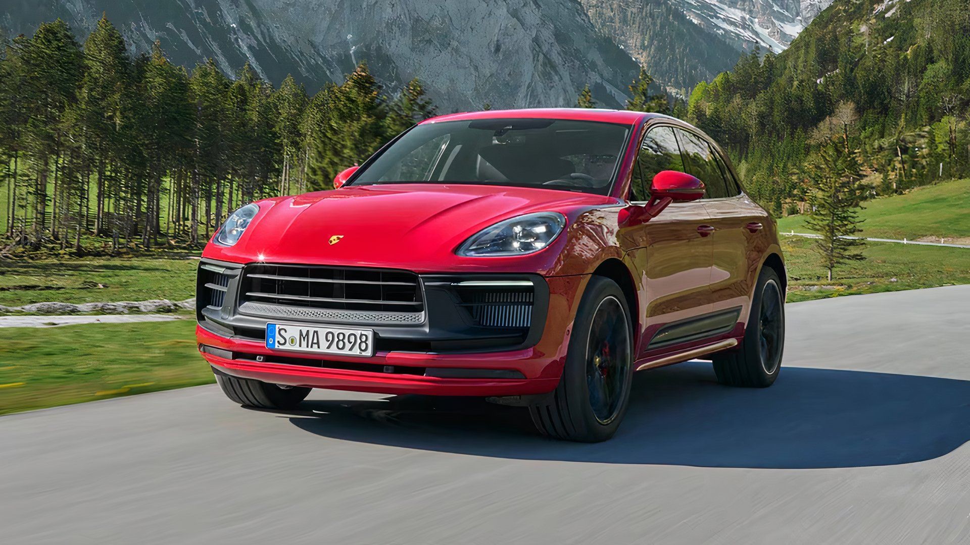 2025 Porsche Macan GTS in red driving on country road with mountains in background