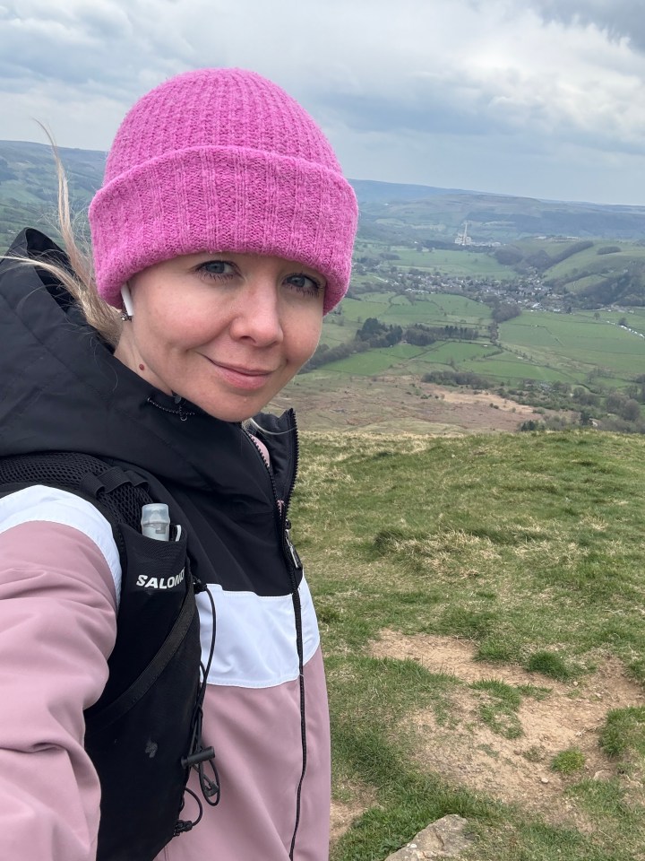 Woman in pink hat hiking, scenic view in background.