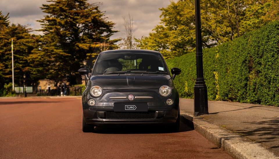 Black Fiat 500 parked on a street.