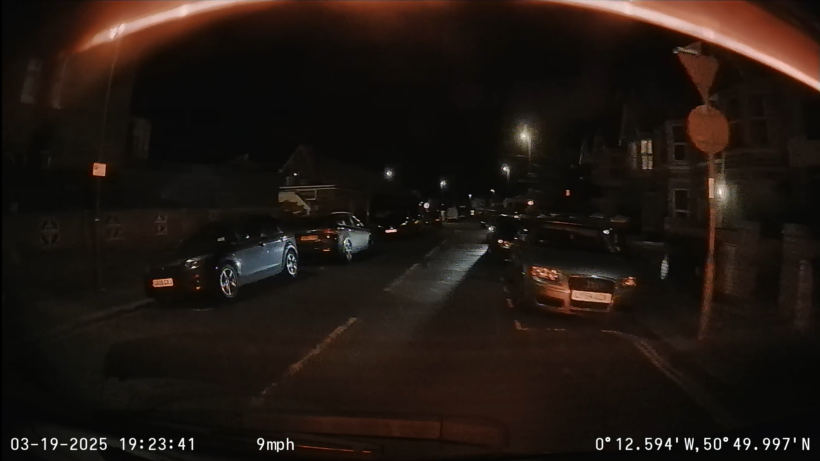 Street lit night view from rear camera. There's not a huge amount of detail, and it's hard to read the number plates of parked cars.
