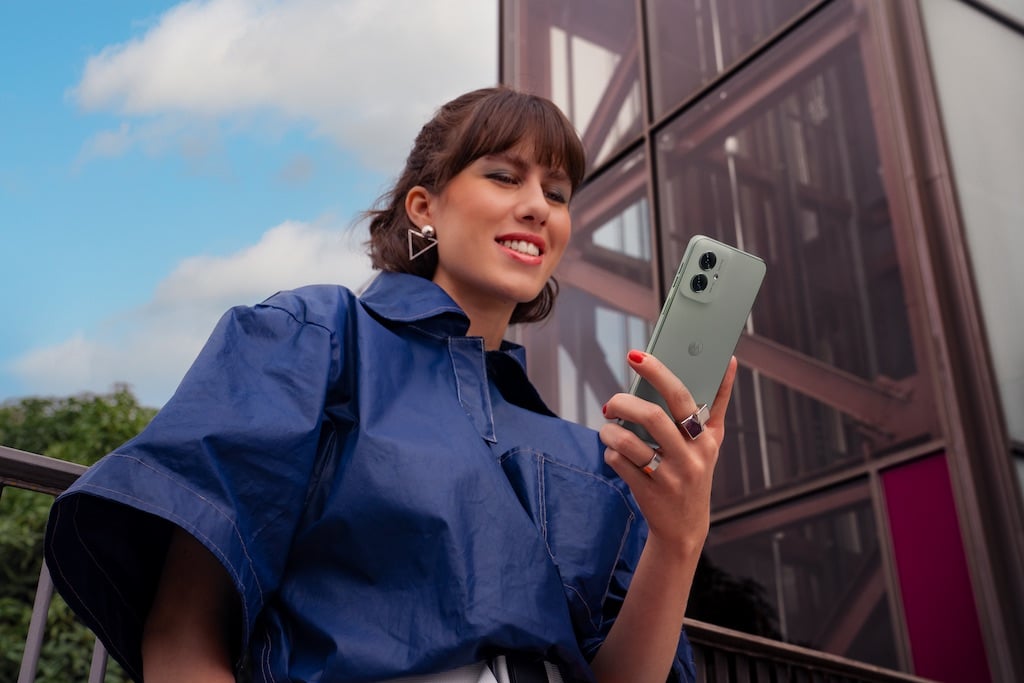 Smiling woman holding Moto G55 phone