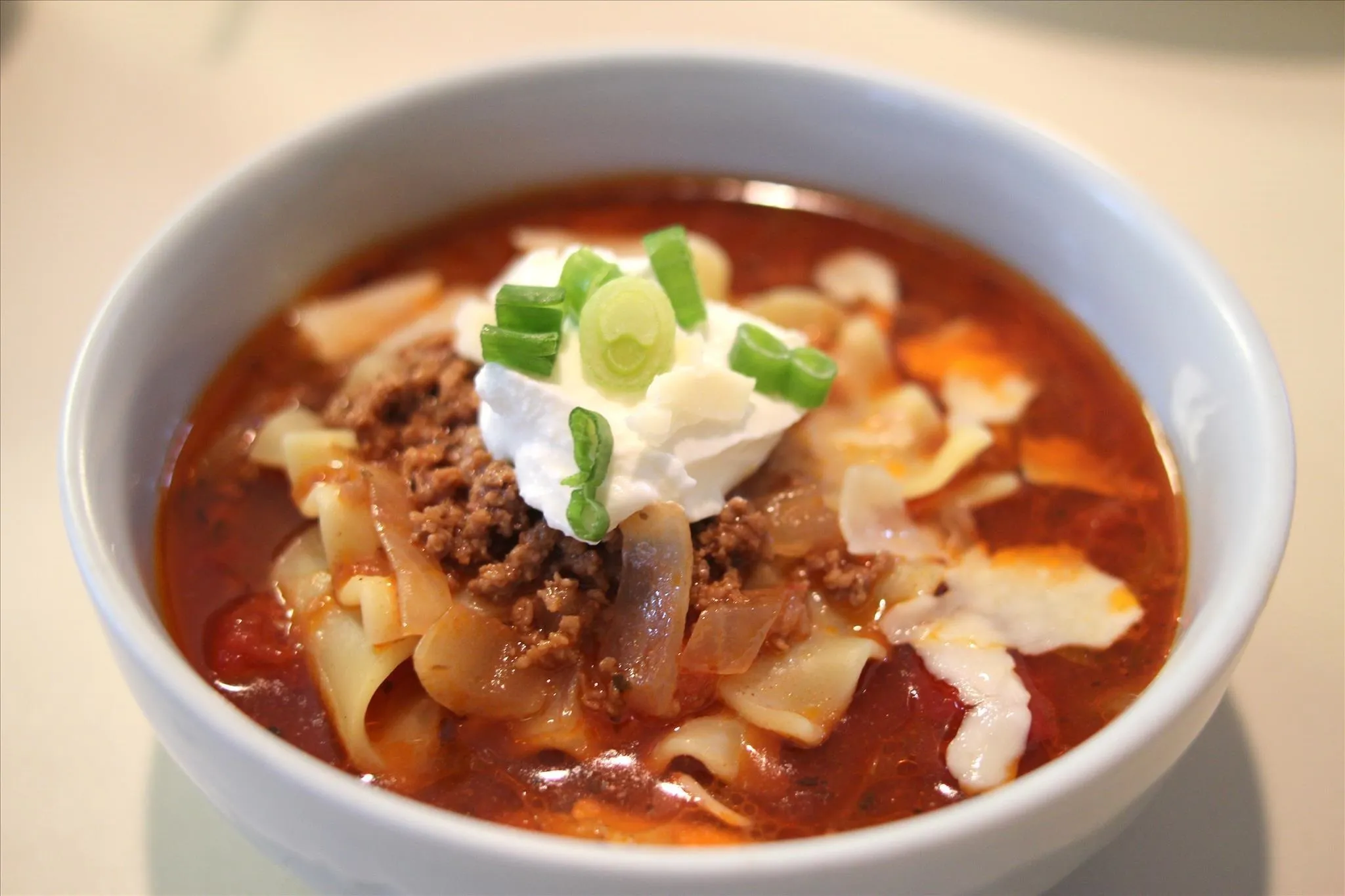 A bowl of hearty chili topped with sour cream and green onions.