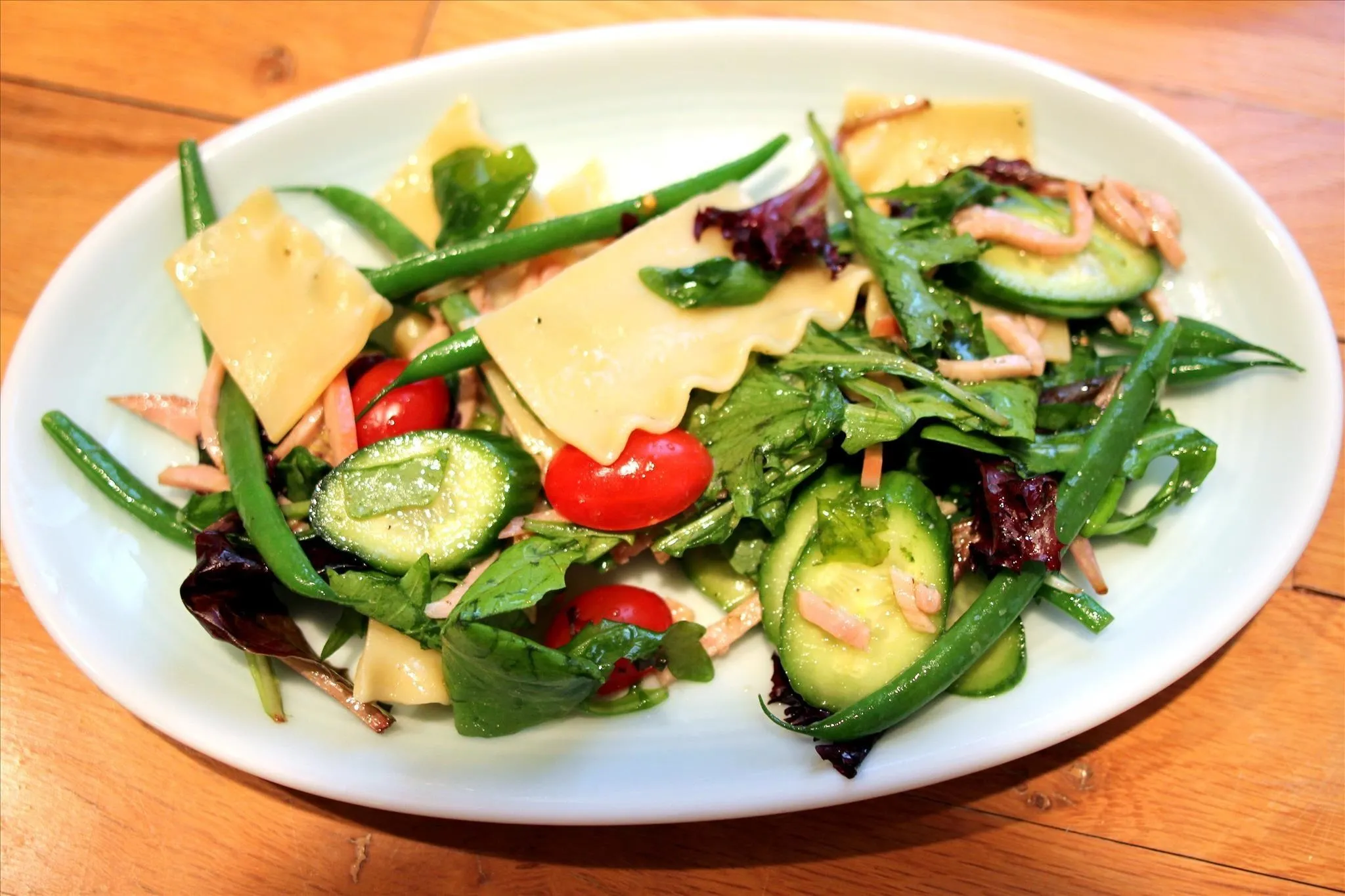Fresh mixed salad with pasta, cucumbers, cherry tomatoes, and greens.