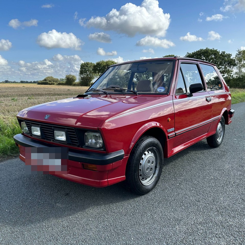 Red Yugo GV hatchback parked on a road.