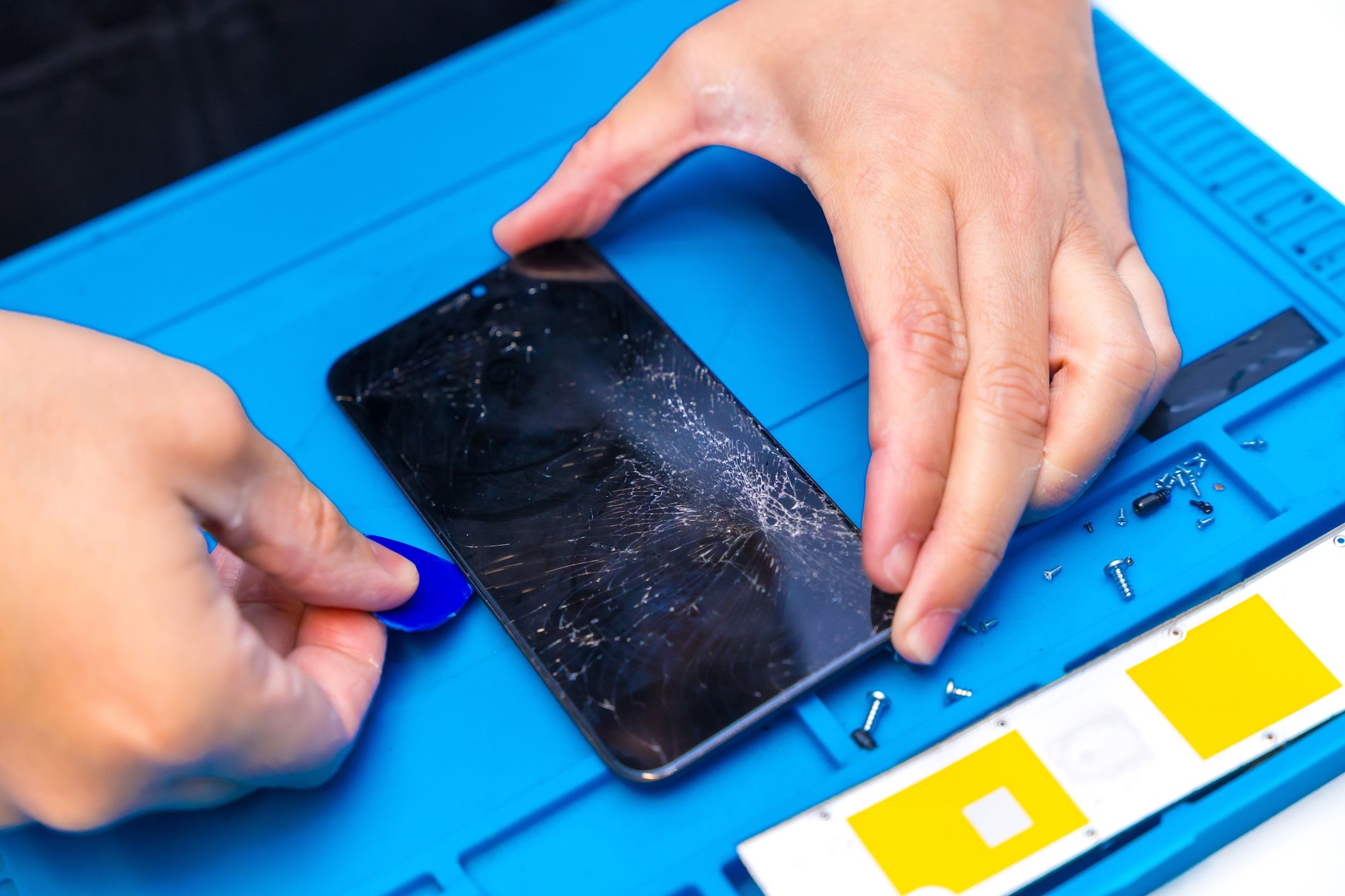 A technician trying to pry open a smartphone for repair