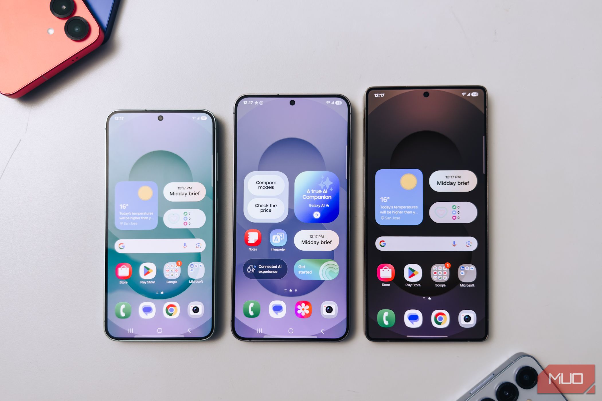 Samsung Galaxy S25 series with their screens on, on white table.