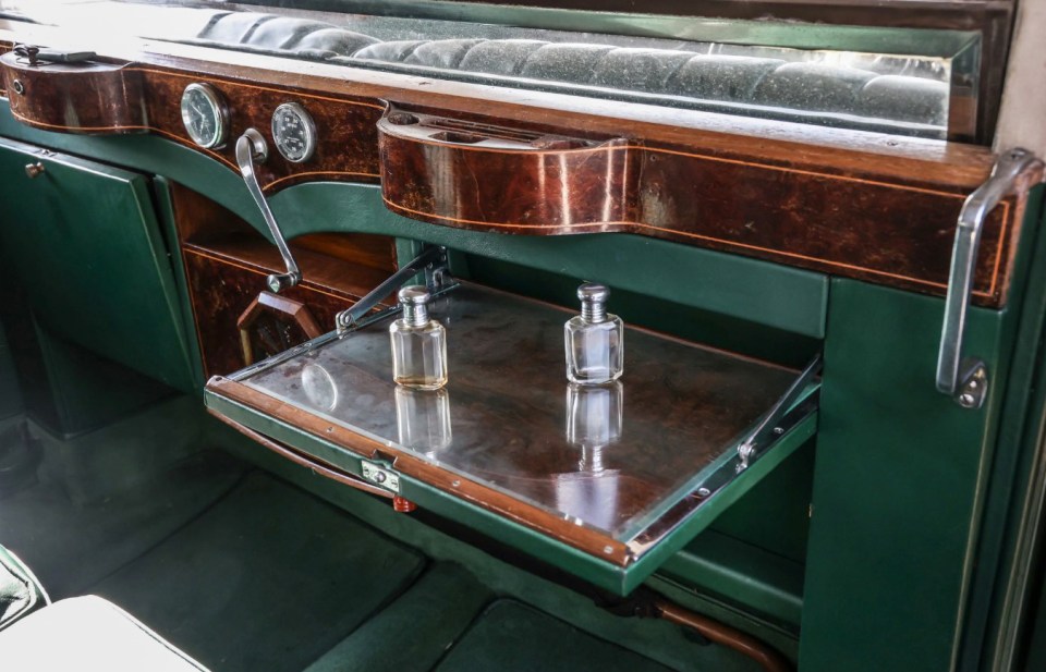 Interior detail of Winston Churchill's 1936 Rolls-Royce Phantom III, showing a fold-down tray with two perfume bottles.