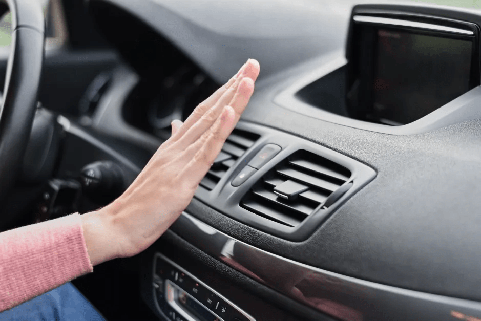 Hand testing car air vent temperature.