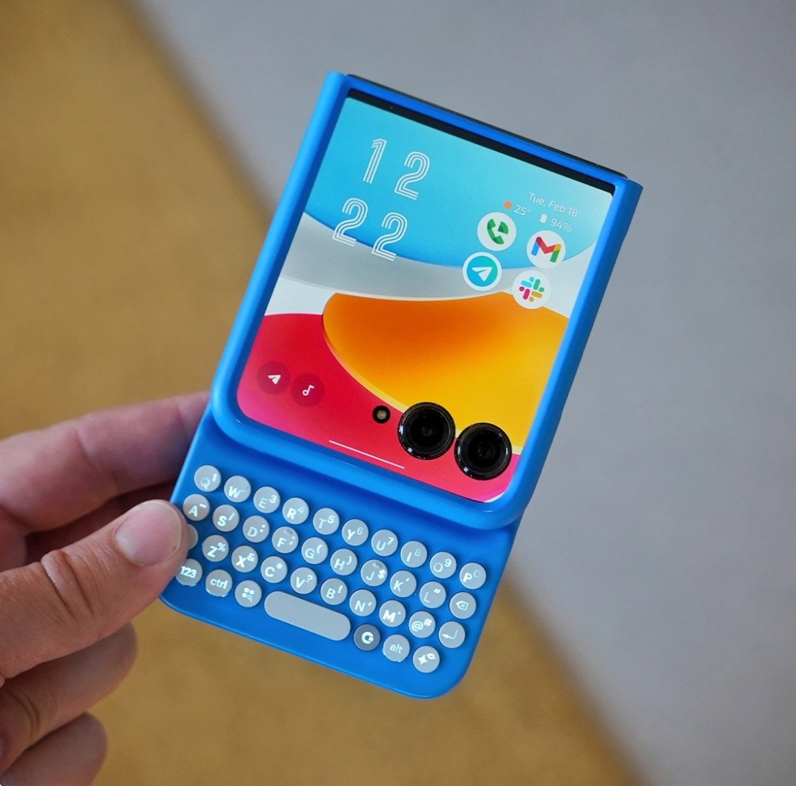 Hand holding foldable phone in blue keyboard case