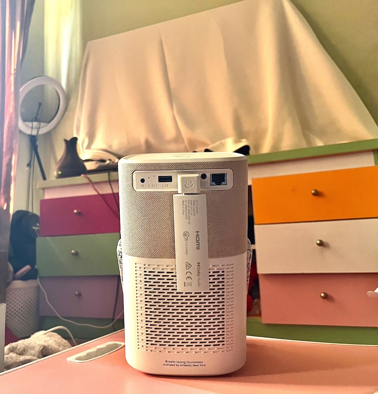 Back view of projector on pink table in colourful room