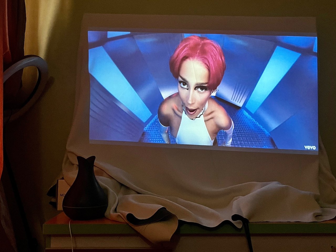 Woman with red wig in music video projected on white sheet