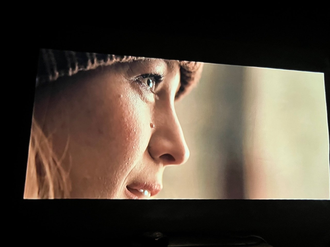 Close up shot of Blake Lively face projected in. dark room