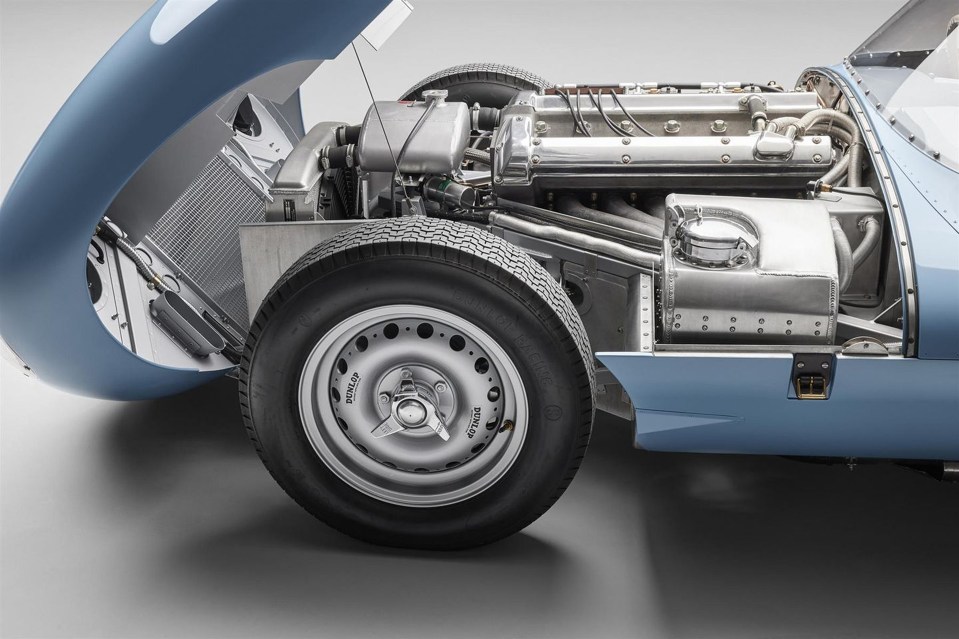 Close-up of a light blue Jaguar D-Type's engine and front wheel.