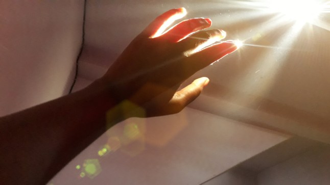 A shot of hand on plain background and effectively captured the sunlight coming through window.