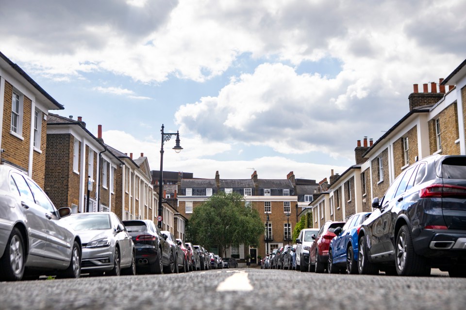 Low-angle view of a residential street in London with parked cars.
