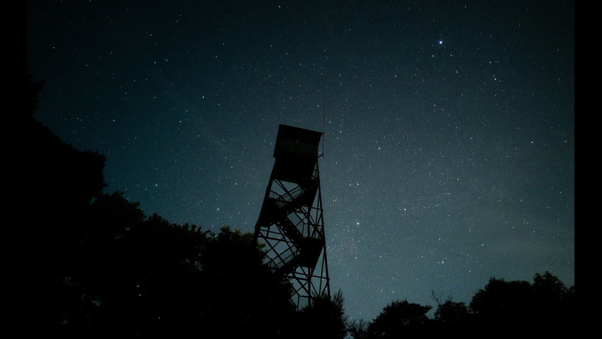A firewatch tower with the night sky in the background.