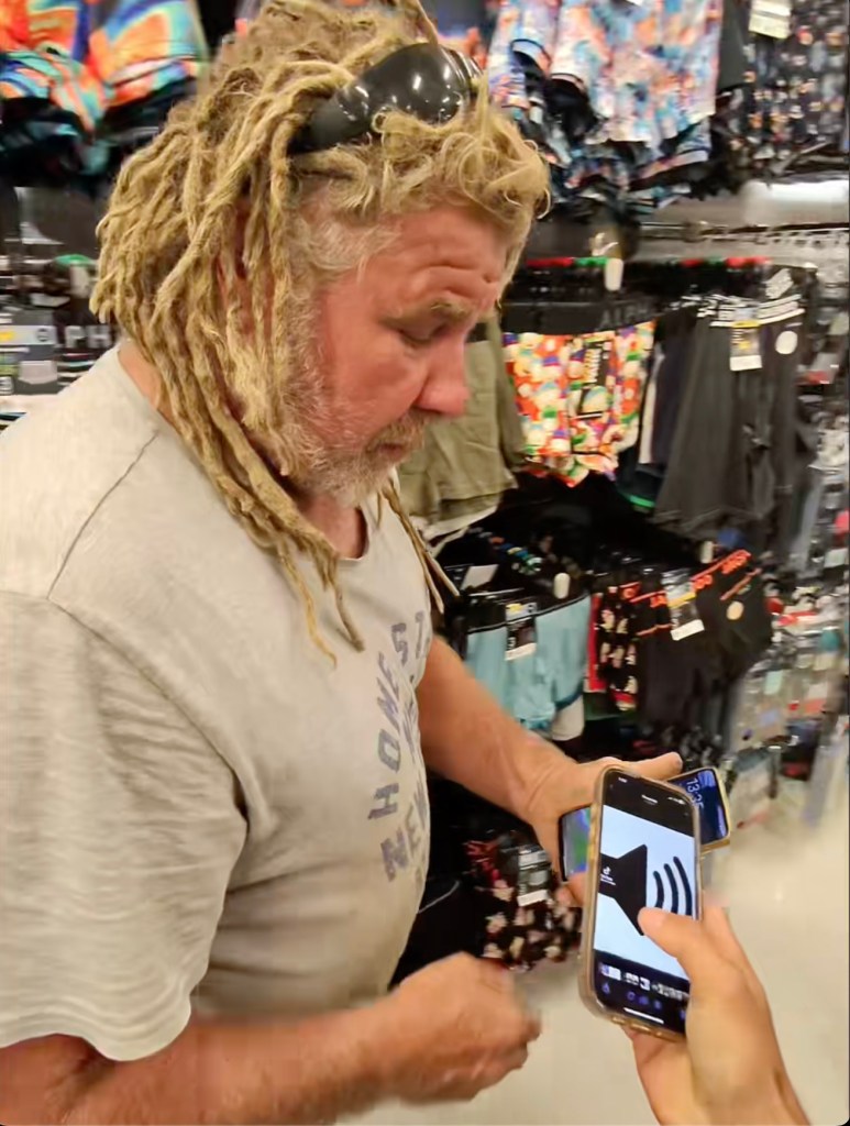 Young man in Adelaide pranking an older man with dreadlocks in a Kmart store by pretending to use Apple Pay on his phone