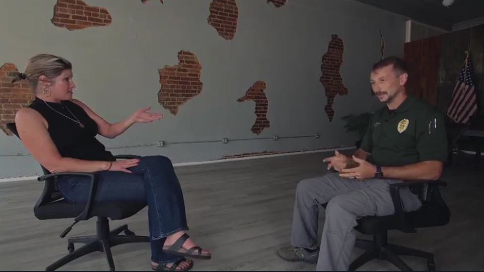A man and woman sit in chairs and talk.