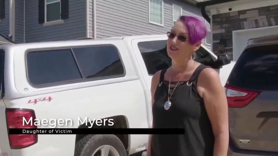 Maegen Myers, daughter of a victim, stands in front of a white truck and a gray SUV.