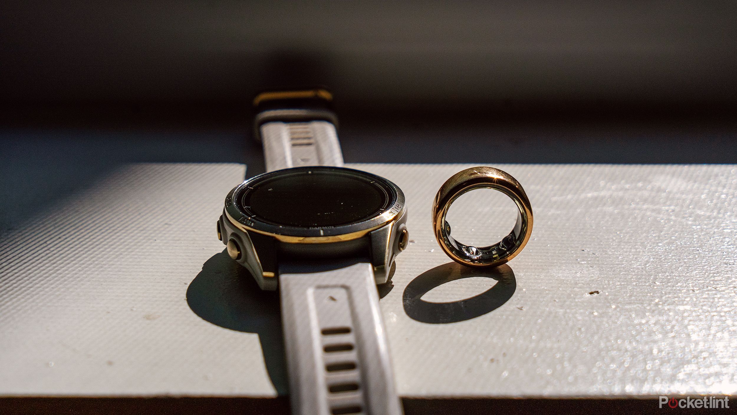 An Oura Ring next to the Garmin epix Pro on a white windowsill.