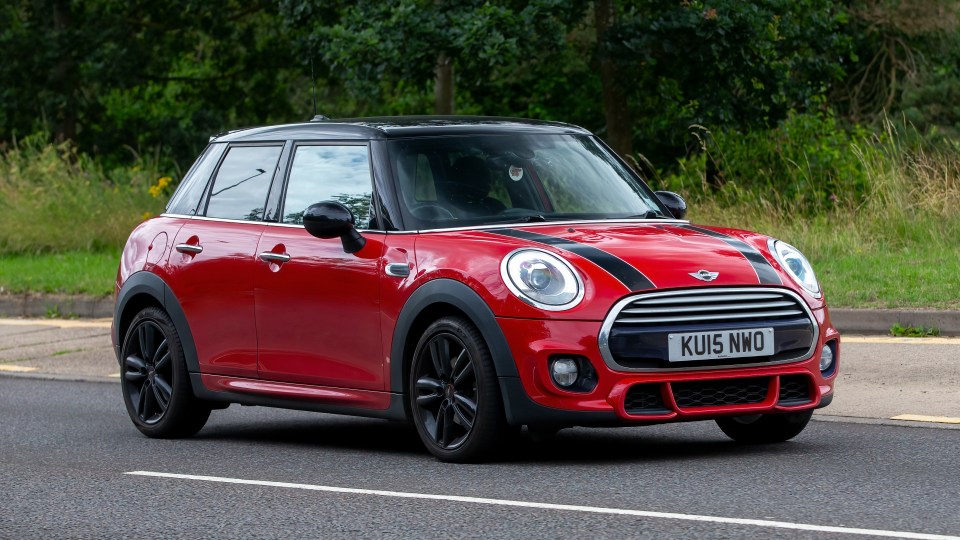 Red Mini Cooper driving on a road.