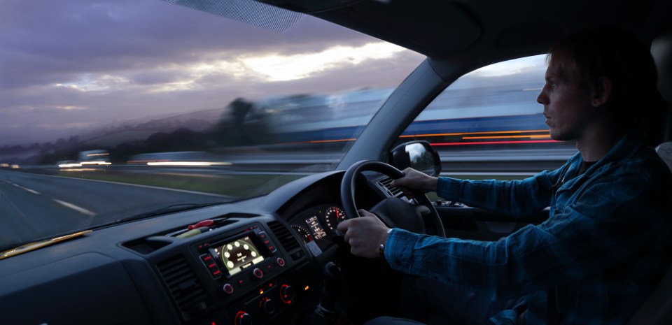 Man driving a van on a motorway at dusk.
