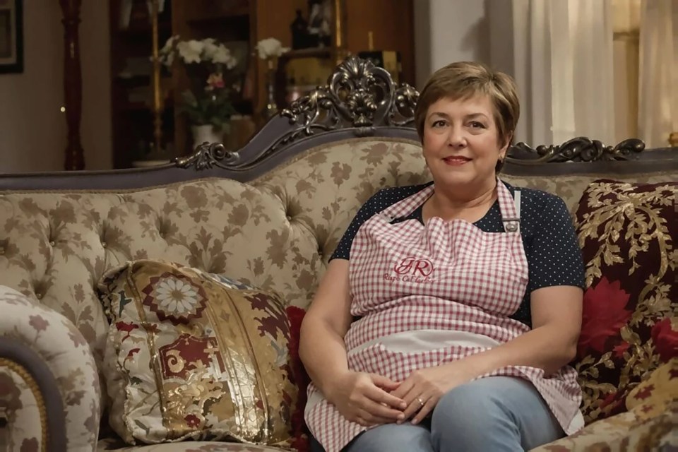 Woman in an apron sitting on an ornate couch.