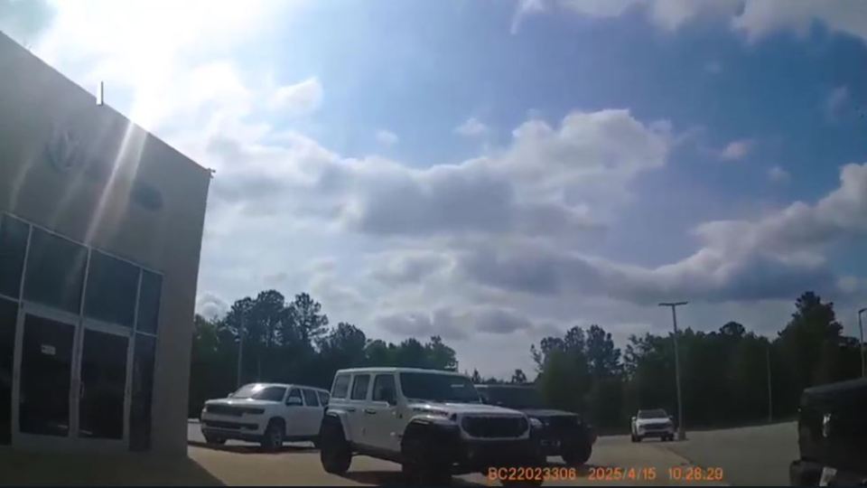 White Jeep and other vehicles parked at a dealership.