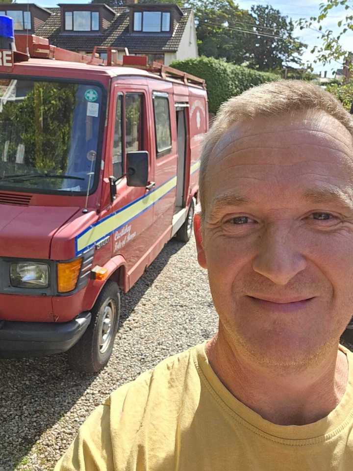Man in yellow shirt with a converted firetruck campervan.