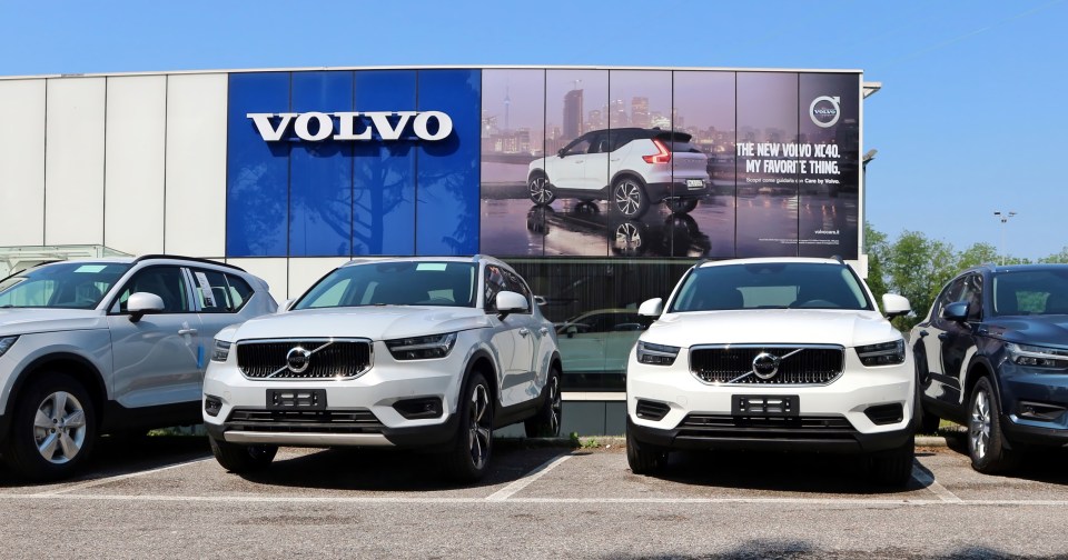 Three white Volvo XC40 SUVs parked in front of a Volvo dealership.