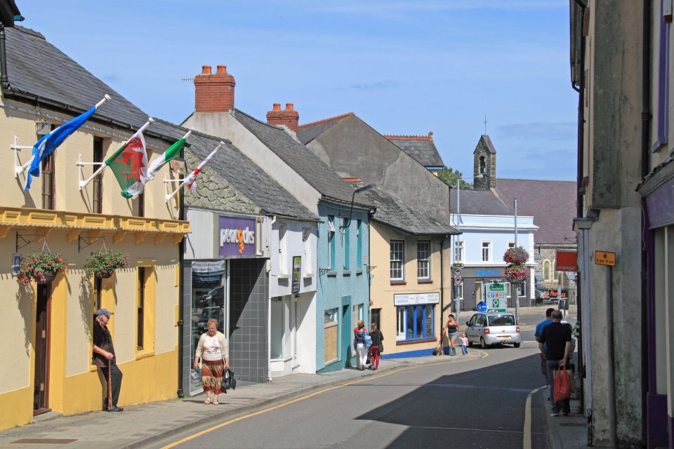 High street in Fishguard, Wales, with shops and pedestrians.