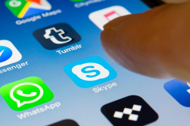A person pressing Skype icon on their phone with their finger.