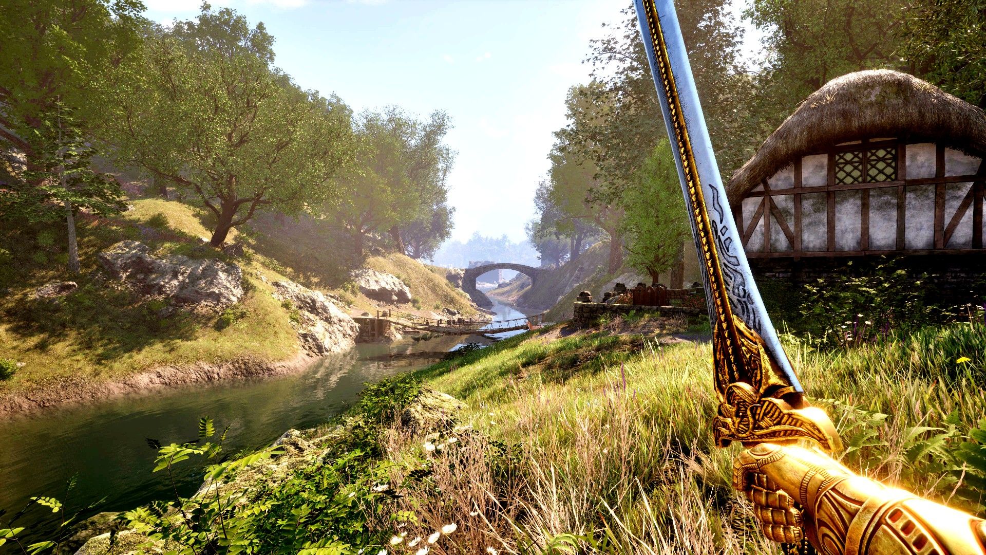 A player holding a sword and looking out at a river next to a house in The Elder Scrolls IV Oblivion Remastered.