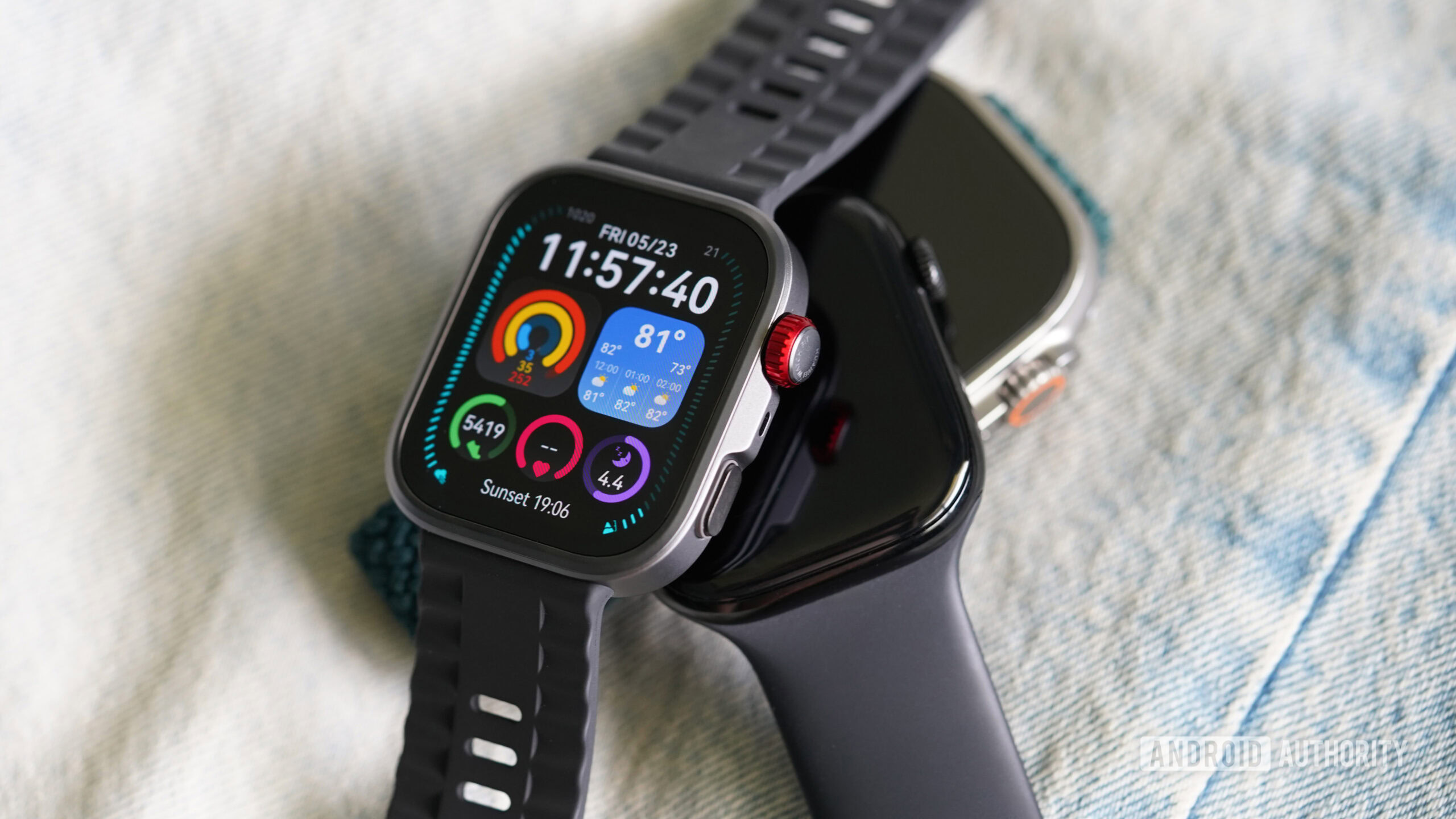 Huawei Watch Fit 4 Pro Apple A Huawei Watch Fit 4 Pro rests on a couple of Apple Watches.