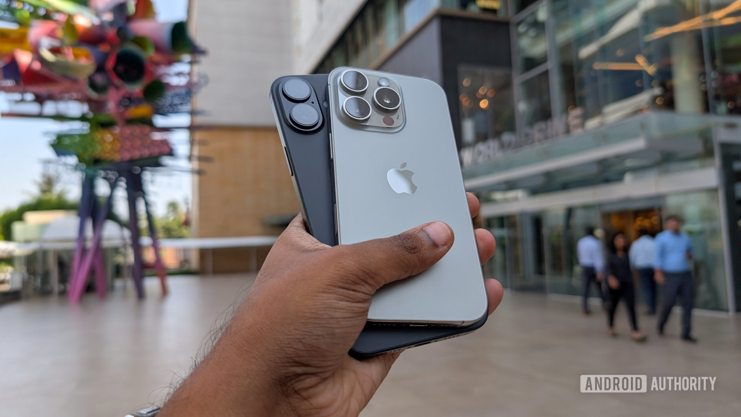 Apple iPhone 16 Plus in black color and iPhone 16 Pro in Natural Titanium color held out in hand Apple iPhone 16 Plus in black color and iPhone 16 Pro in Natural Titanium color held out in hand