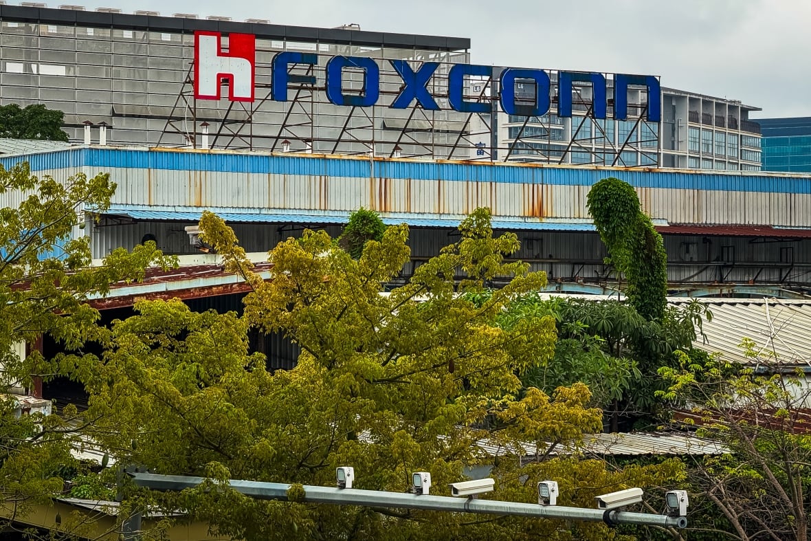 A large white factory building with trees in the foreground.