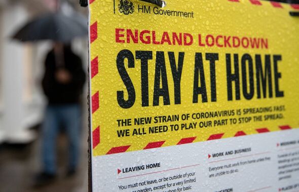 People walk past a Government sign warning people to stay at home on the High street in Winchester, Hampshire