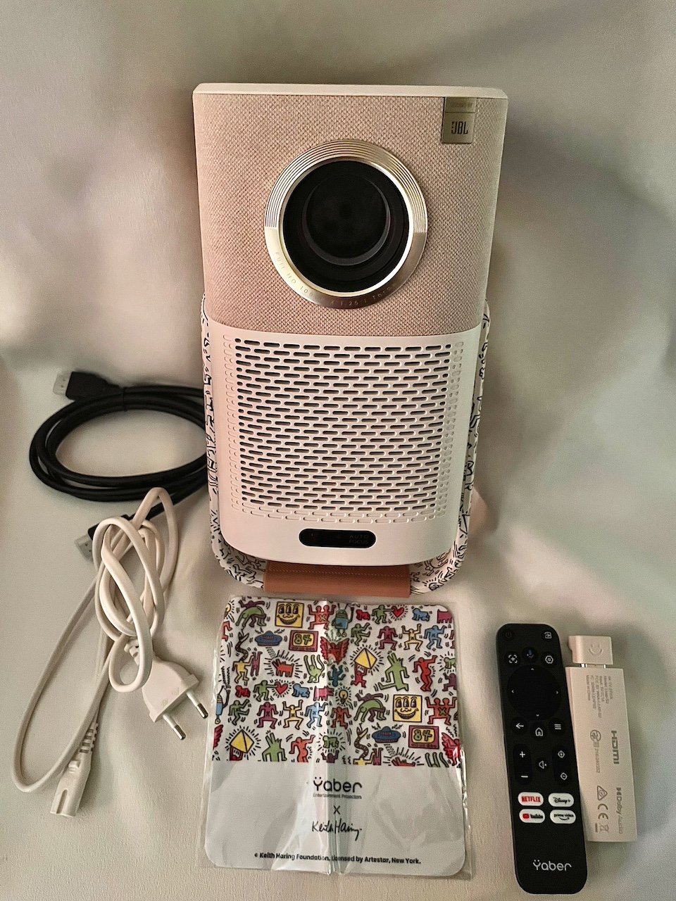 Projector with remote control and accessories in front of it